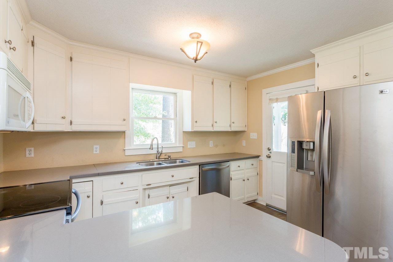 7308 Wilderness Road Raleigh, NC 27613 - Photo 7 of 25 a kitchen with white cabinets and refrigerator
