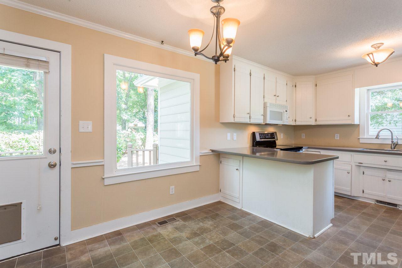 7308 Wilderness Road Raleigh, NC 27613 - Photo 8 of 25 a kitchen with granite countertop white cabinets a sink a window and stainless steel appliances