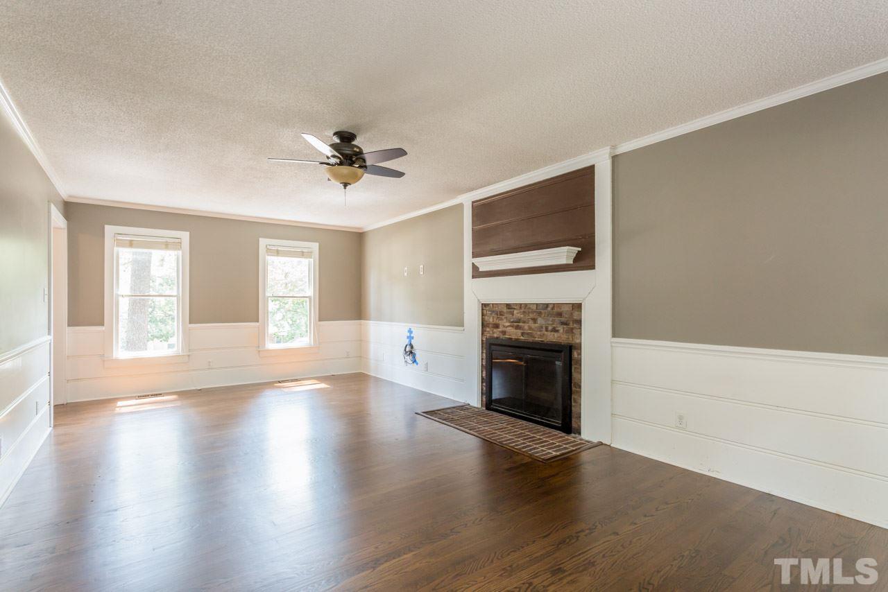 7308 Wilderness Road Raleigh, NC 27613 - Photo 10 of 25 an empty room with windows fireplace and wooden floor
