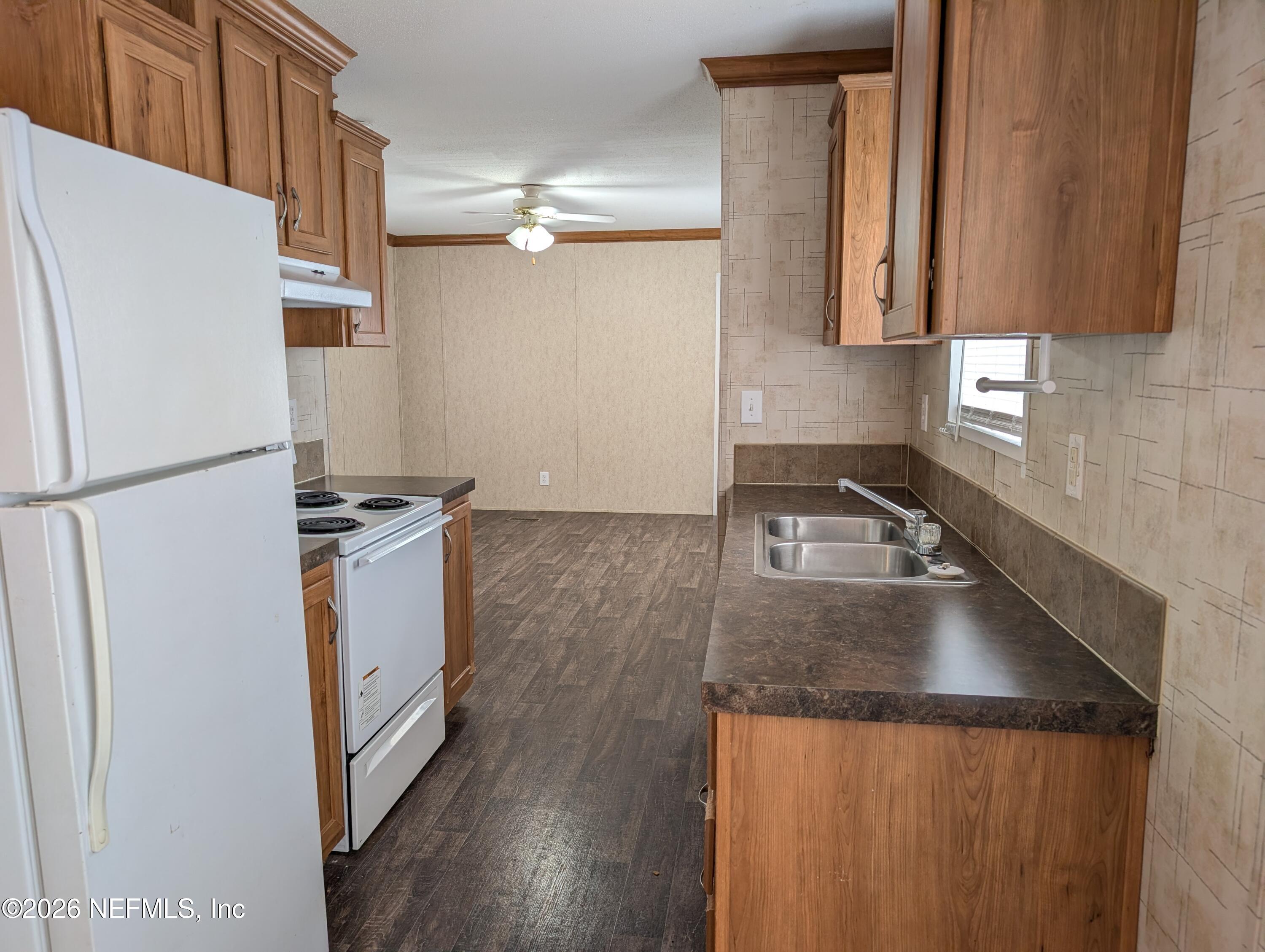 125 Hayman Drive Interlachen, FL 32148 - Photo 3 of 14 a kitchen with granite countertop a refrigerator a sink and white cabinets