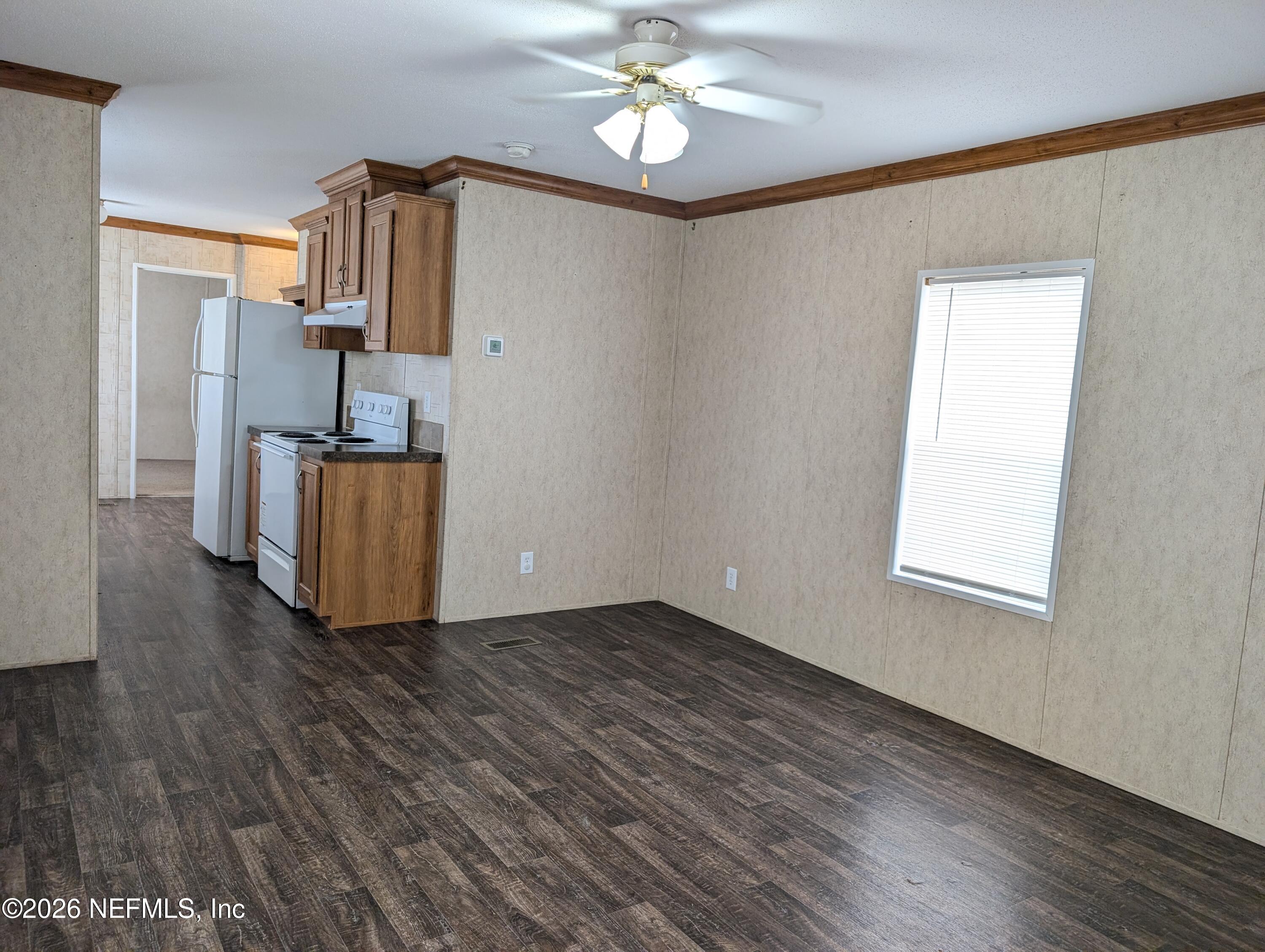 125 Hayman Drive Interlachen, FL 32148 - Photo 4 of 14 a view of a kitchen with wooden floor a ceiling fan and windows