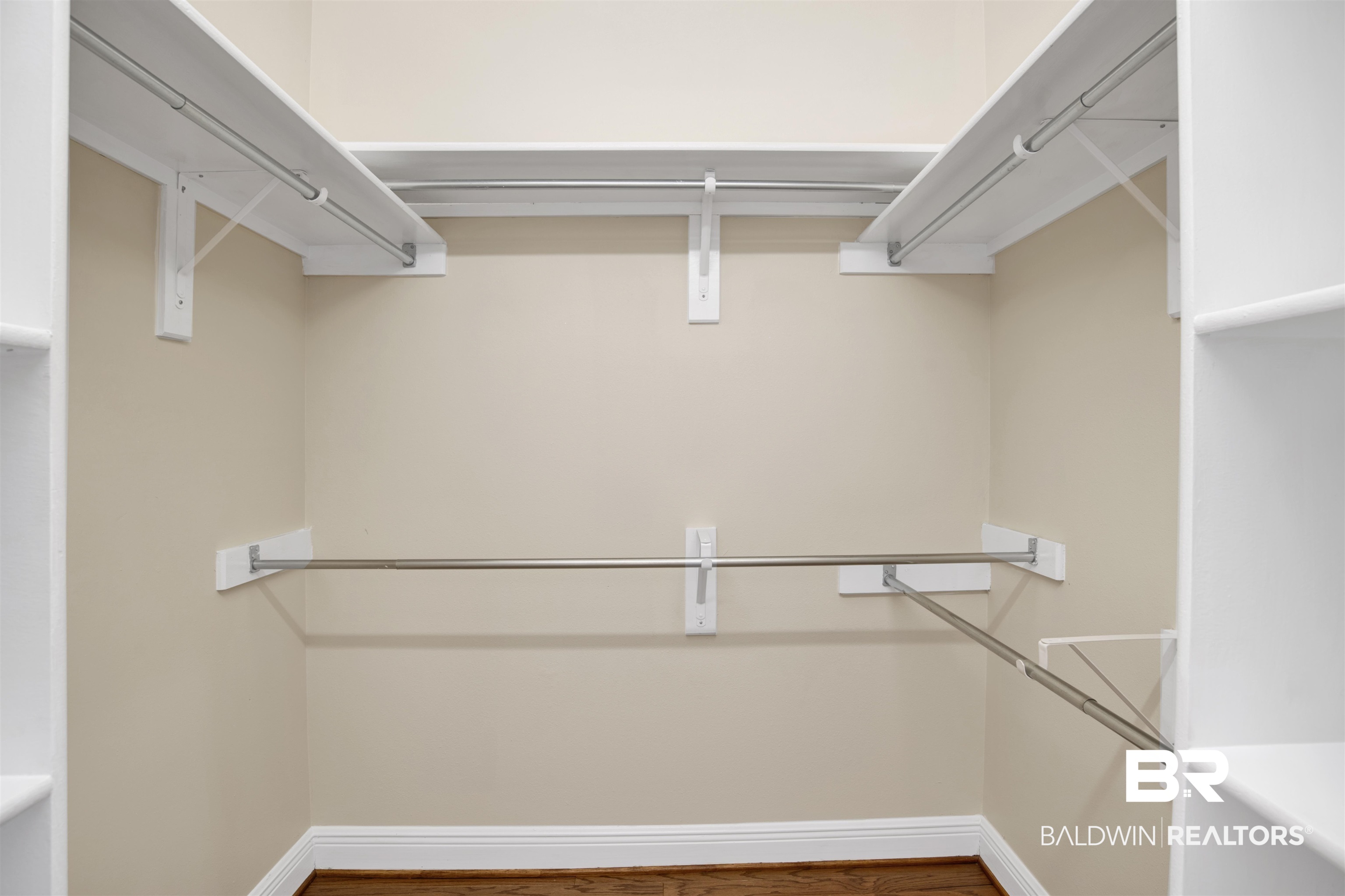 8847 Dawes Lake Road South Mobile, AL 36619 - Photo 24 of 47 Walk-in closet featuring light beige walls, wood-finish flooring, white baseboards, and built-in white shelving with chrome hanging rods