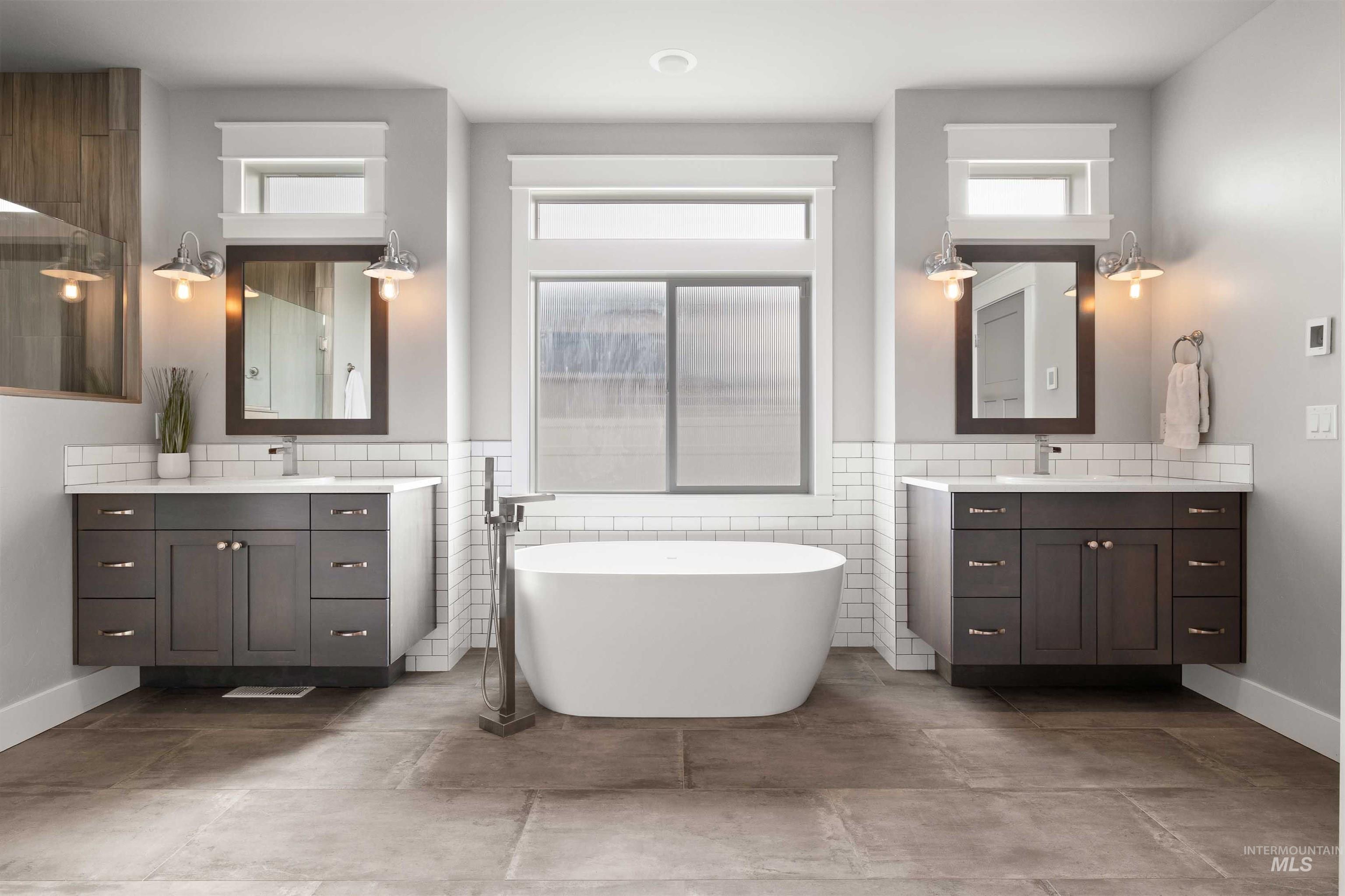 2441 Blick Lane Twin Falls, ID 83301 - Photo 16 of 50 Bathroom featuring two vanities, wainscoting, tile walls, healthy amount of natural light, and a freestanding bath