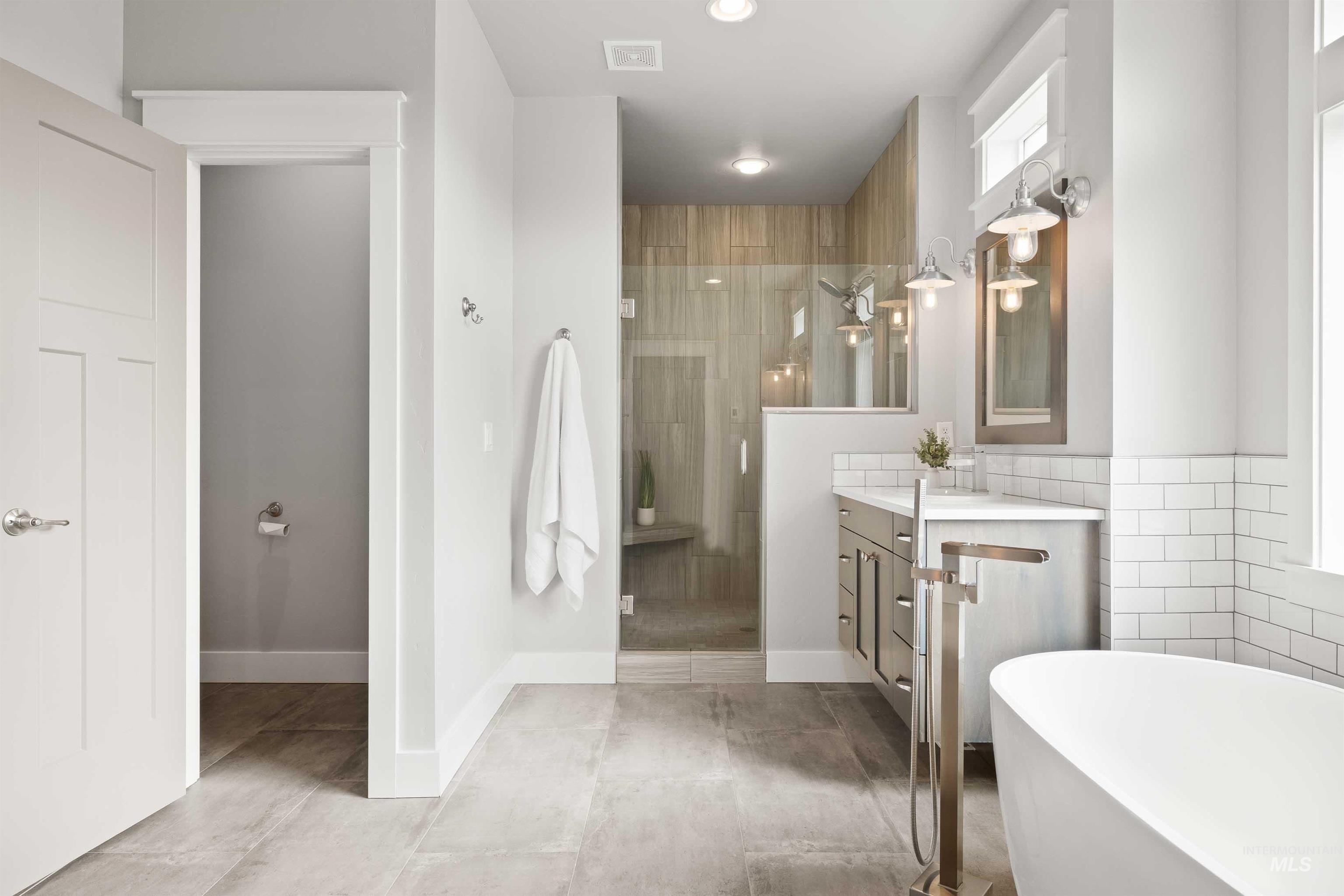 2441 Blick Lane Twin Falls, ID 83301 - Photo 17 of 50 Bathroom featuring a freestanding tub, a shower stall, vanity, and tile walls