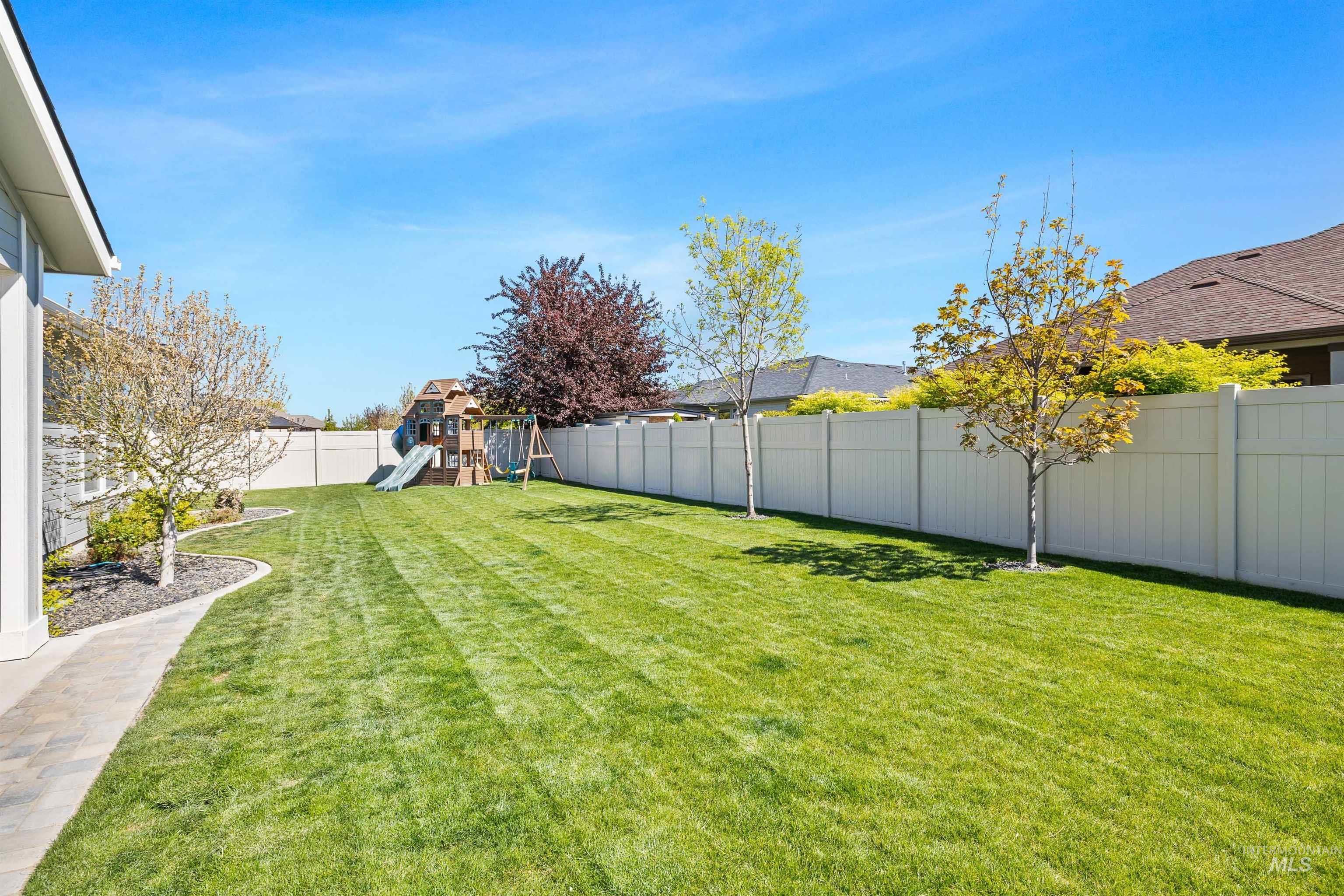 2441 Blick Lane Twin Falls, ID 83301 - Photo 39 of 50 Spacious lawn area featuring a white privacy fence, mature trees, and a paved pathway