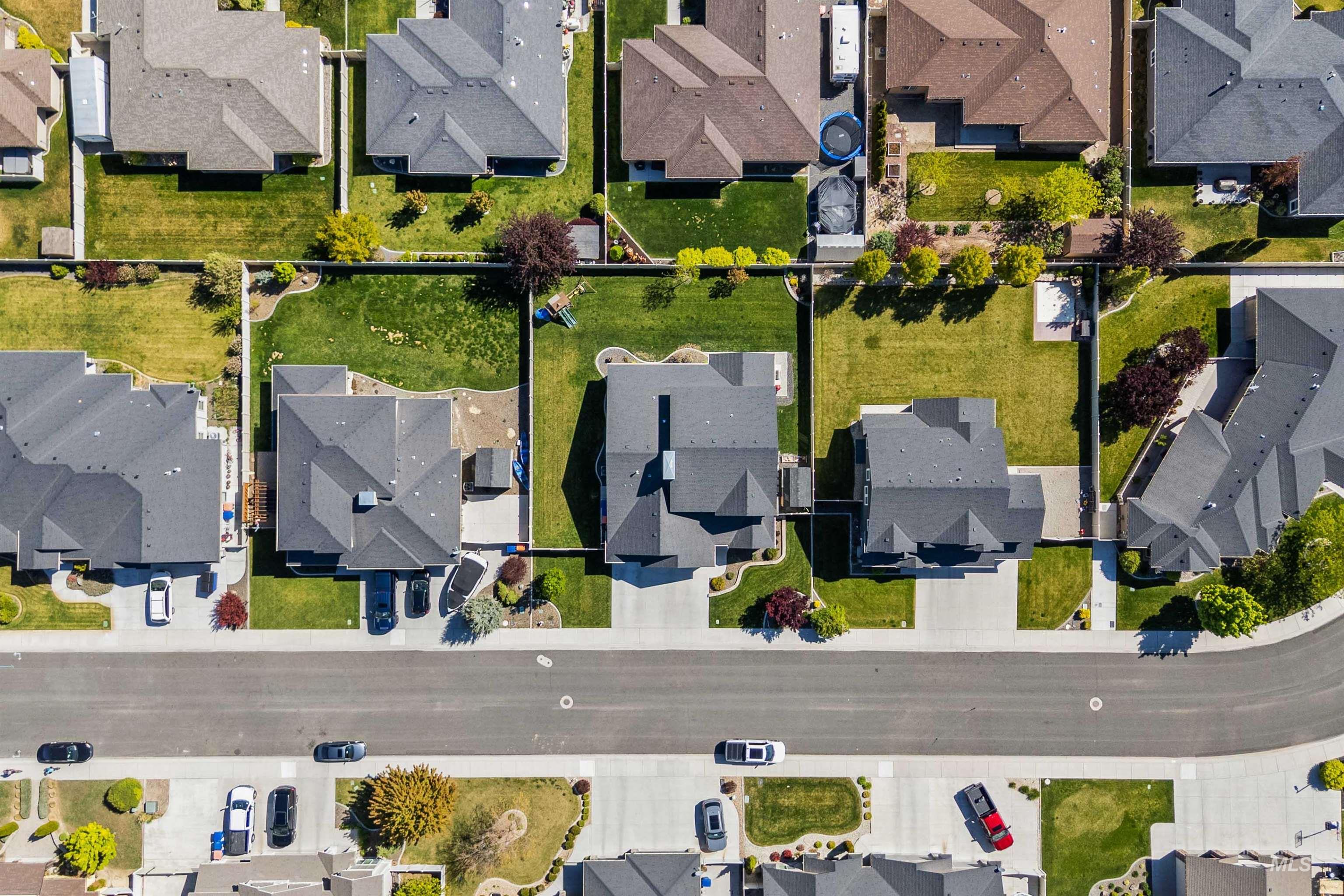 2441 Blick Lane Twin Falls, ID 83301 - Photo 49 of 50 Aerial view of a residential property featuring a dark-toned gable roof, a paved driveway, and a fenced backyard with a green lawn