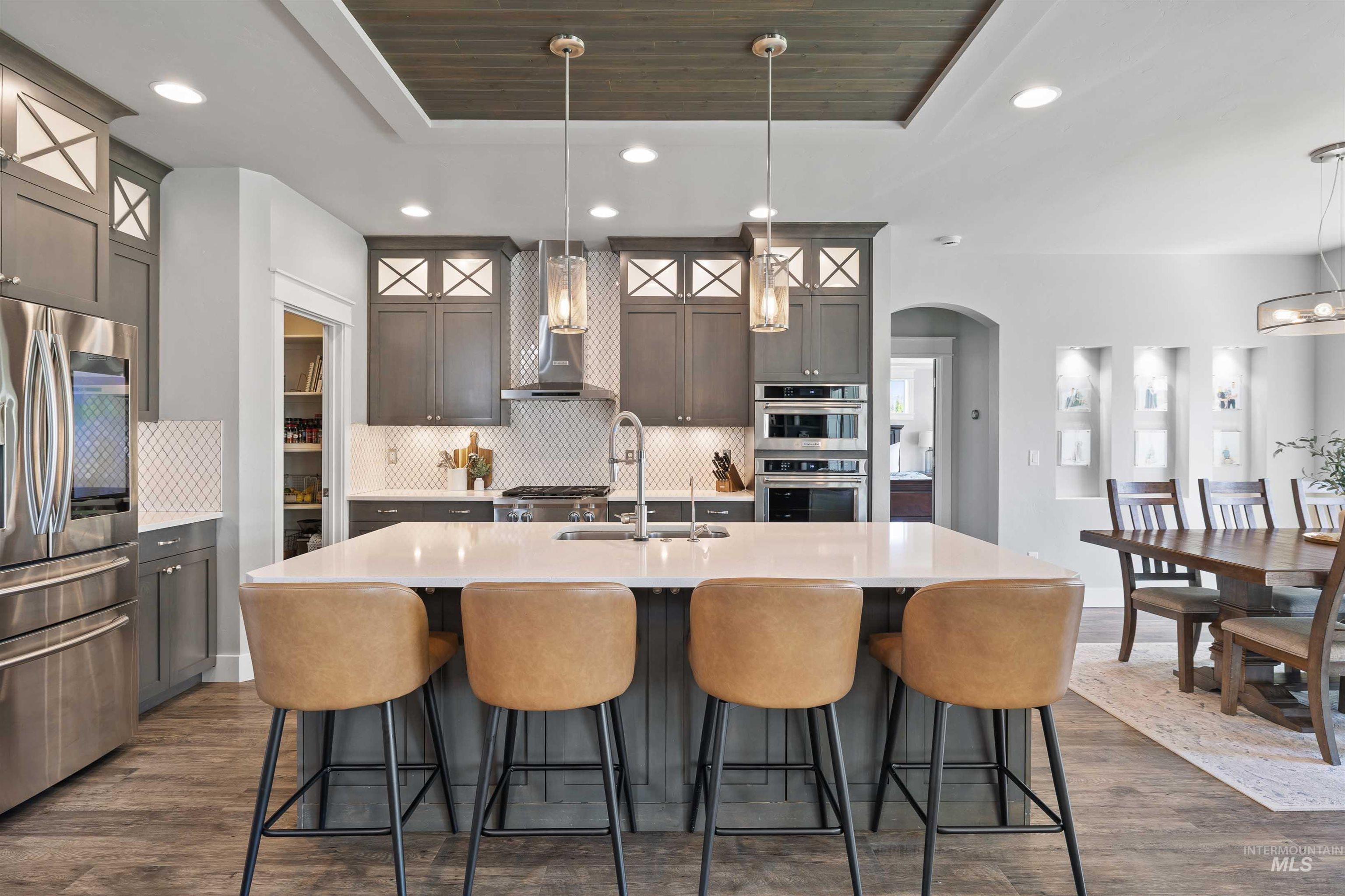 2441 Blick Lane Twin Falls, ID 83301 - Photo 8 of 50 Expansive kitchen island with a light-toned countertop, stainless steel appliances, herringbone tile backsplash, and a wood-finish coffered ceiling