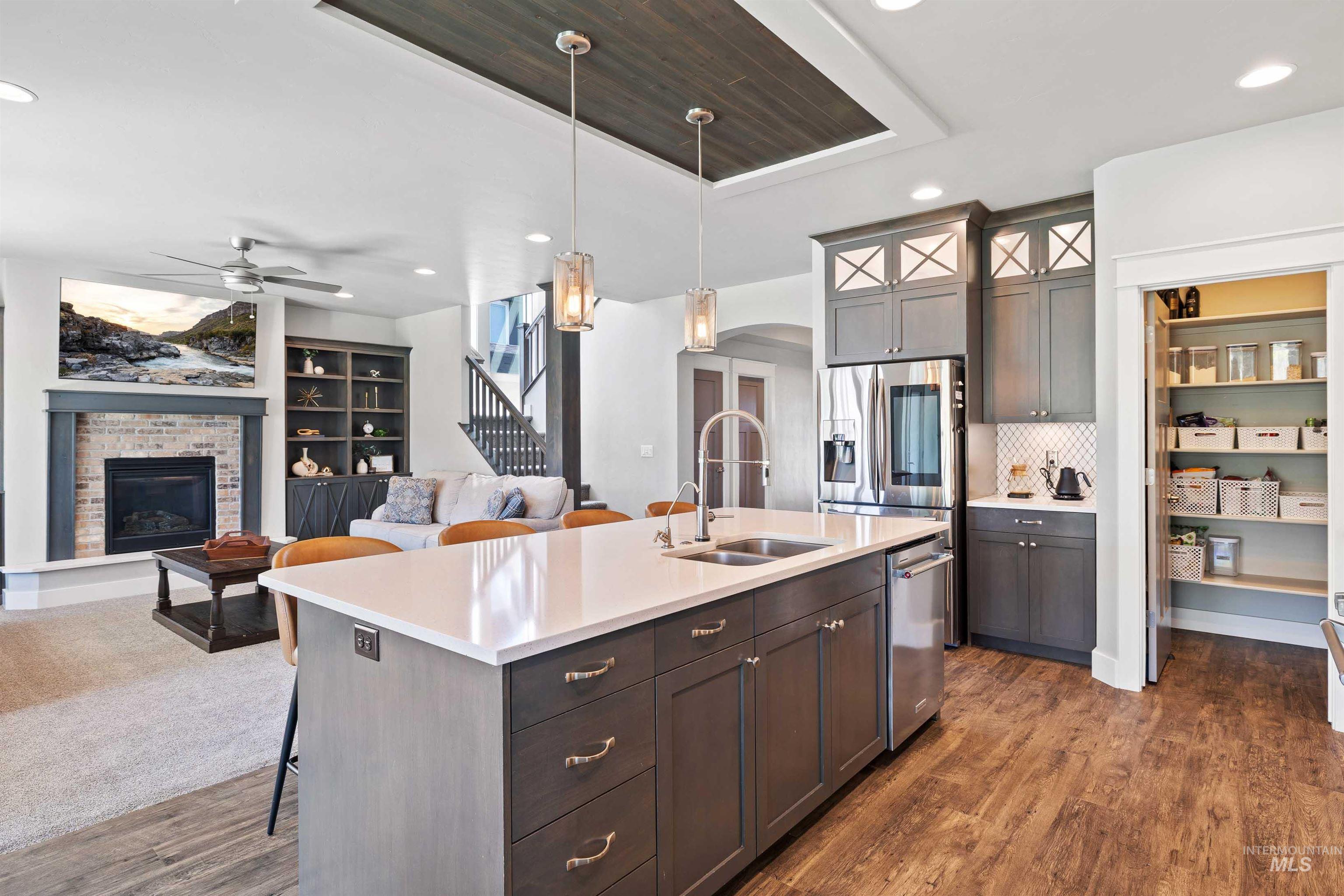 2441 Blick Lane Twin Falls, ID 83301 - Photo 10 of 50 Gourmet kitchen featuring a large island with an undermount double sink, stainless steel appliances, grey cabinetry with upper decorative glass panels, and a walk-in pantry