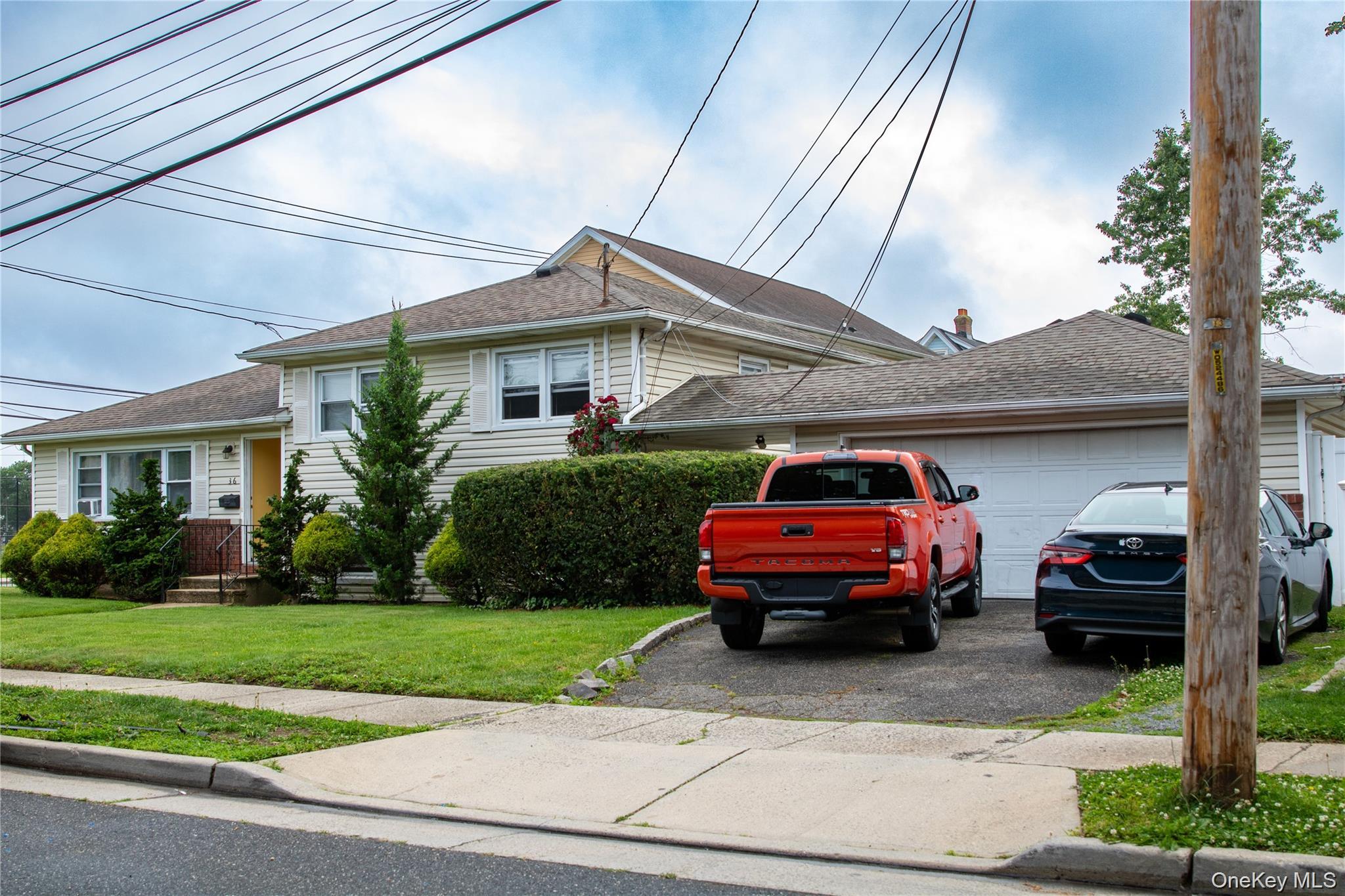 36 Monroe Place Hempstead, NY 11550 - Photo 4 of 5 Split level home with a front lawn, asphalt driveway, a shingled roof, and an attached garage