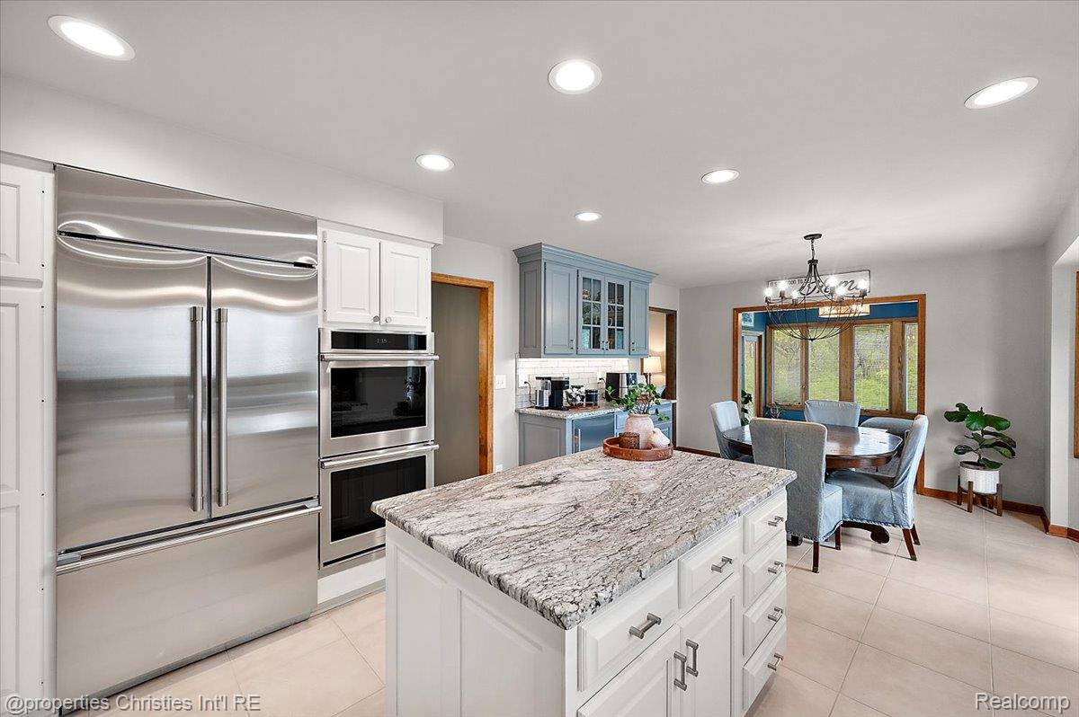 1071 Woodbridge Lane Rochester, MI 48306 - Photo 16 of 76 Kitchen with stainless steel appliances, a center island, white cabinets, hanging lights, and glass fronted cabinets