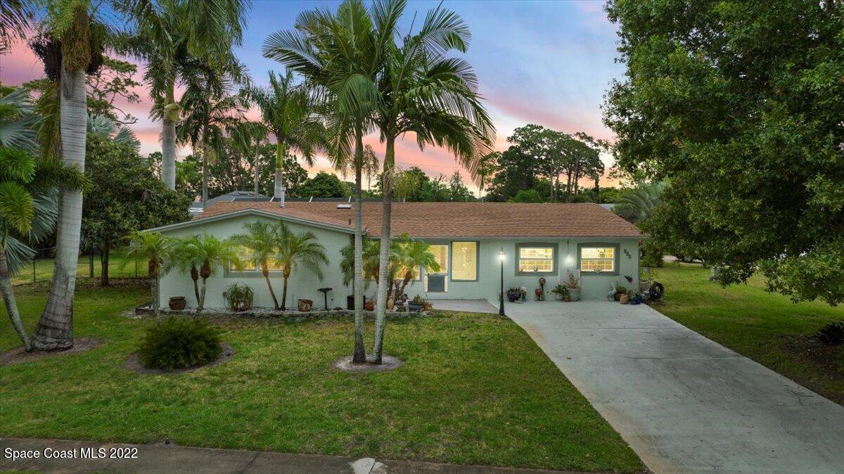 a front view of a house with garden and trees