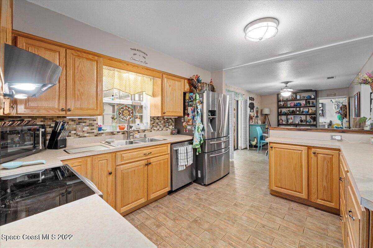 960 Kings Post Road Rockledge, FL 32955 - Photo 9 of 39 a large kitchen with stainless steel appliances kitchen island granite countertop a refrigerator oven a sink dishwasher and white cabinets with wooden floor