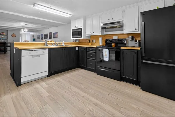 a kitchen with stainless steel appliances granite countertop a refrigerator a stove top oven a sink dishwasher and white cabinets with wooden floor