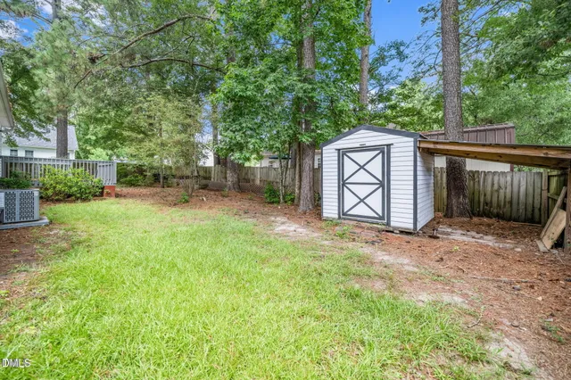 a view of a backyard with a large tree and wooden fence