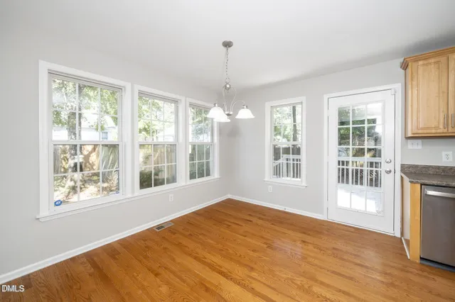 a view of an empty room with a window and wooden floor