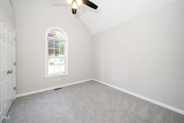 an empty room with ceiling fan and window