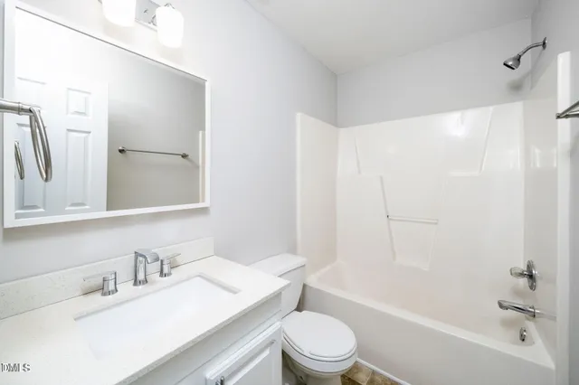 a bathroom with a bathtub shower sink vanity mirror and toilet