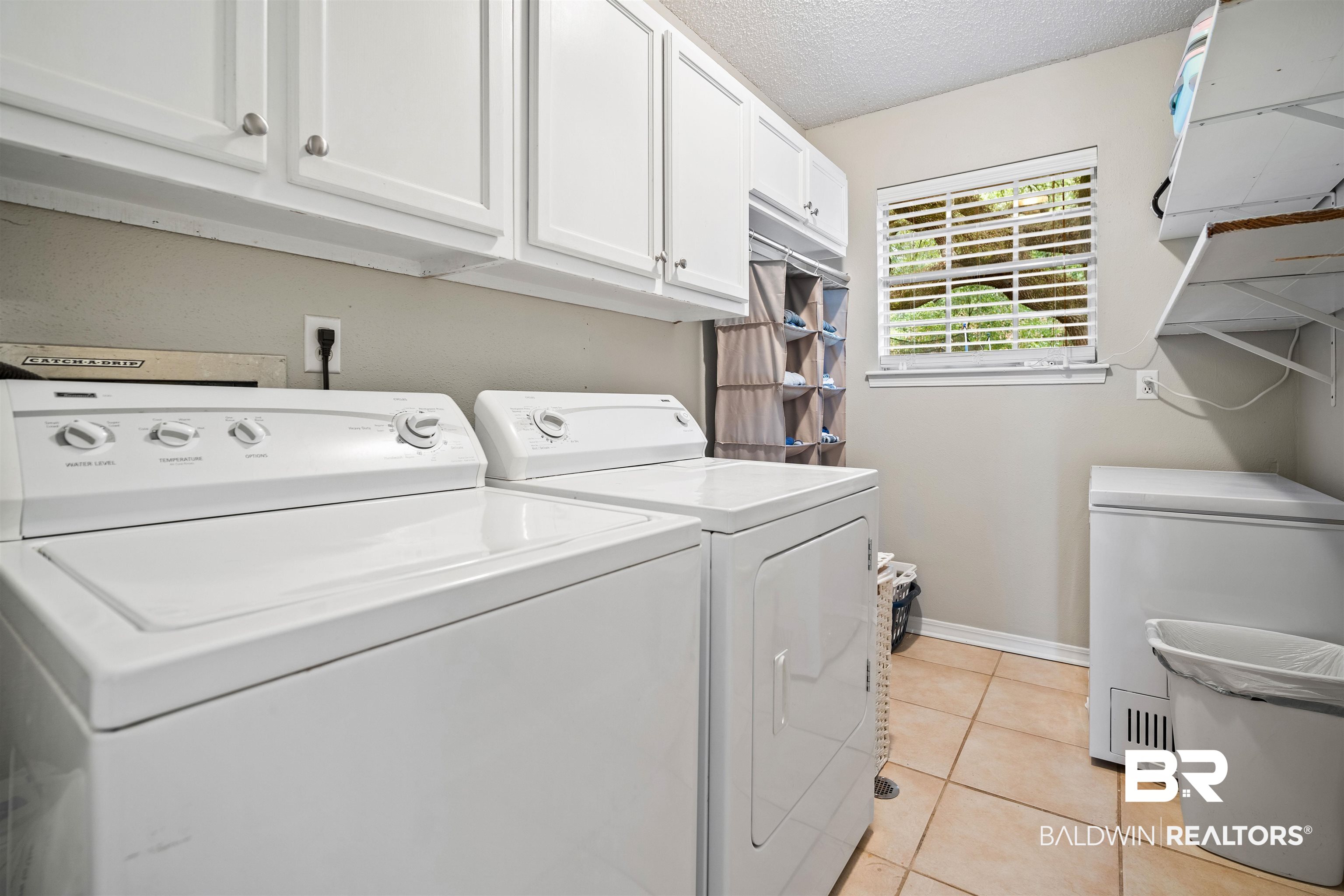 4228 Spring Valley Drive South Mobile, AL 36693 - Photo 24 of 31 Washroom featuring cabinets, light tile patterned floors, a textured ceiling, and washing machine and dryer