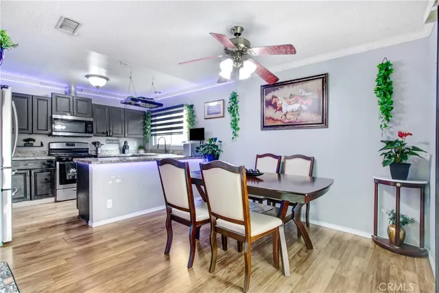 a kitchen with stainless steel appliances kitchen island granite countertop a dining table chairs and a refrigerator