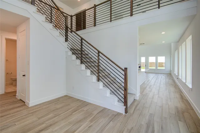 an entryway in a hall with wooden floor and a window