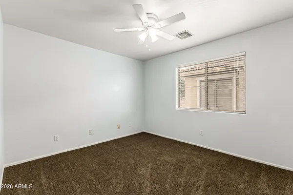an empty room with a chandelier fan and windows