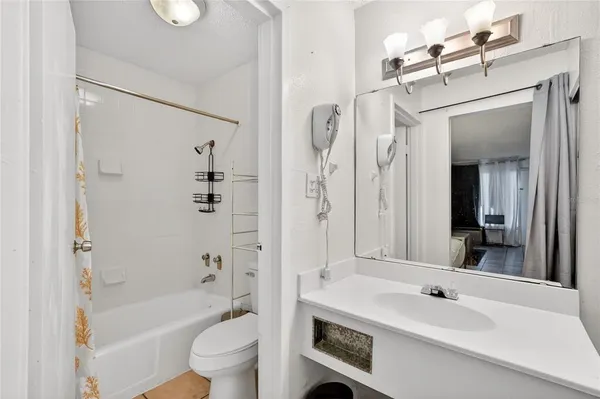 a bathroom with a sink a toilet a mirror a bathtub and shower