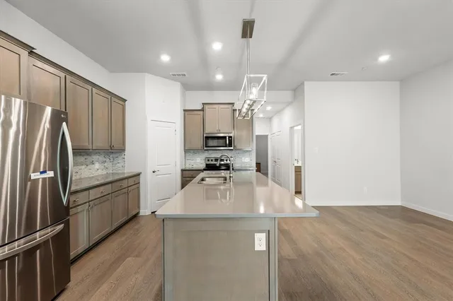 a kitchen with kitchen island a counter top space a sink stainless steel appliances and cabinets