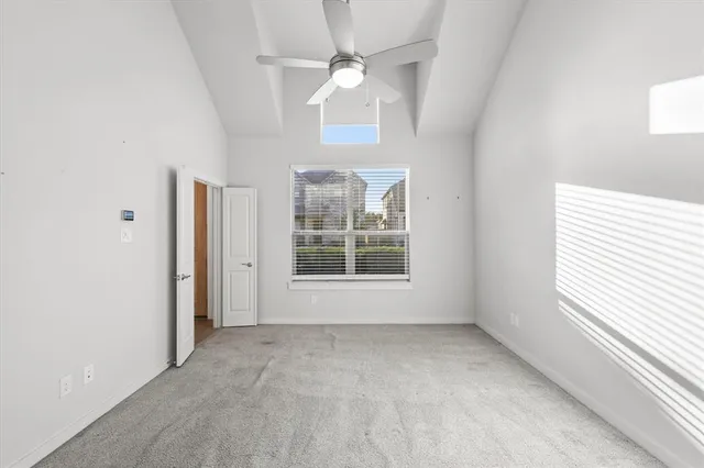 an empty room with chandelier fan and windows