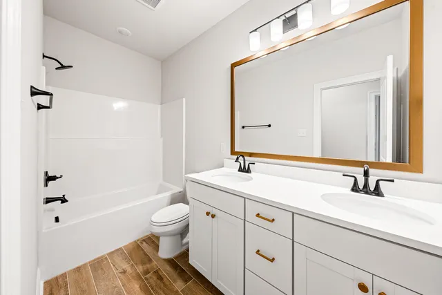 a bathroom with a sink a toilet a large mirror and shower