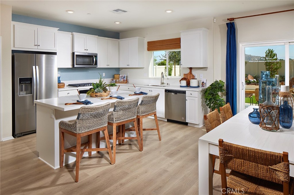 2090 El Nido Avenue Perris, CA 92571 - Photo 5 of 19 a kitchen with a table chairs refrigerator and microwave