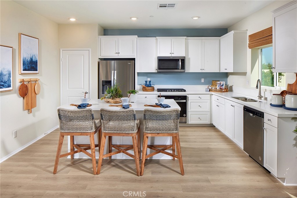 2090 El Nido Avenue Perris, CA 92571 - Photo 6 of 19 a kitchen with stainless steel appliances kitchen island granite countertop a table chairs microwave and sink