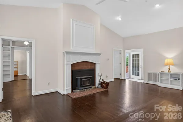 a view of an empty room with wooden floor fireplace and a window