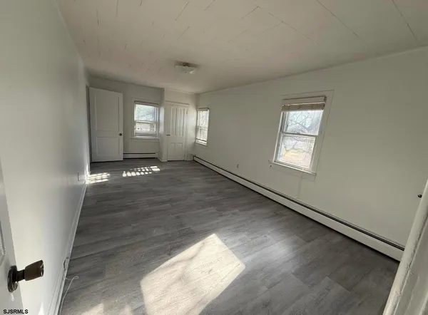 a view of an empty room and window and wooden floor