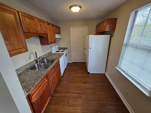 a kitchen with sink a refrigerator and wooden cabinets