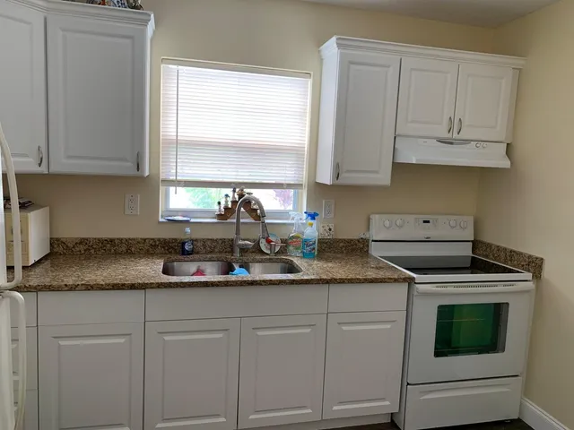 a kitchen with granite countertop white cabinets and white stainless steel appliances