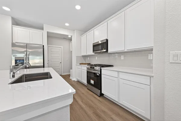 a kitchen with granite countertop white cabinets and stainless steel appliances