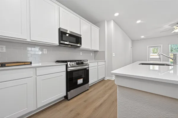 a kitchen with stainless steel appliances granite countertop a sink a stove a microwave and cabinets