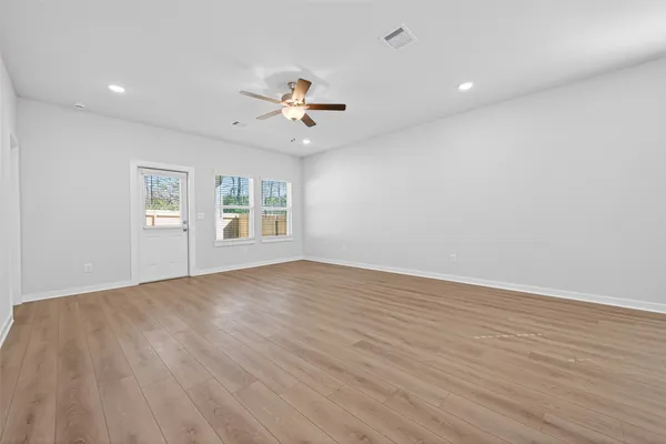 a view of an empty room with a window and wooden floor
