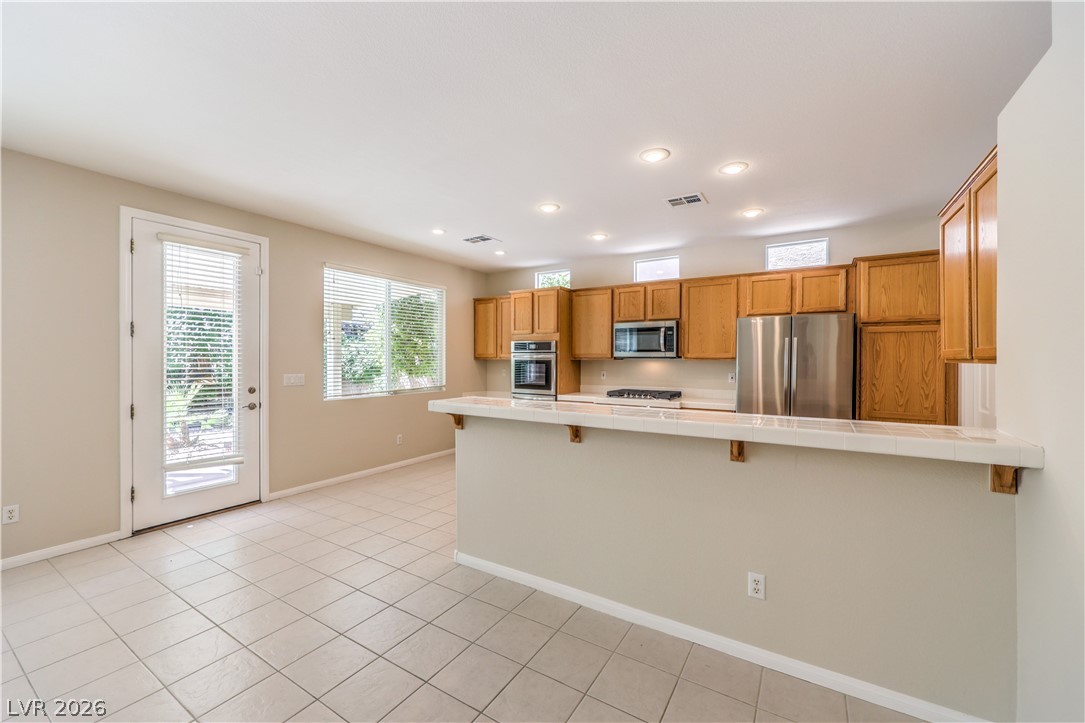 3713 Spring Shadow Road Las Vegas, NV 89129 - Photo 13 of 37 A well-equipped kitchen features tile flooring and ample cabinetry, offering a bright and functional space for culinary endeavors.