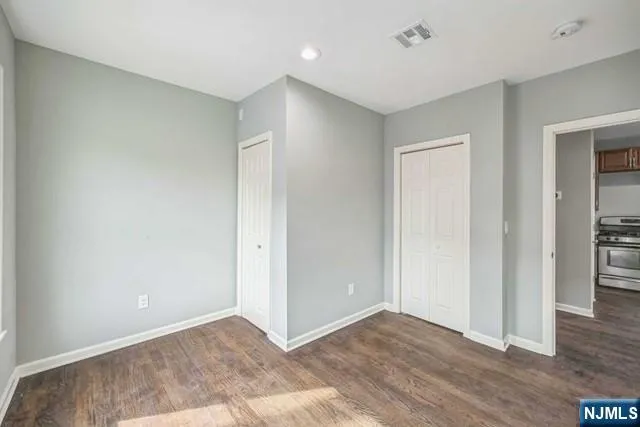 a view of an empty room with wooden floor and closet