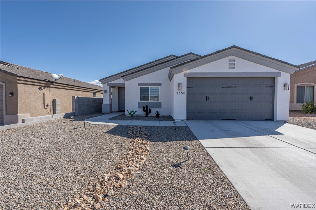 3550 North Kenneth Road Kingman, AZ 86409 - Photo 2 of 41 a view of a grey house with a yard and large tree