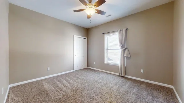 an empty room with closet and a chandelier fan