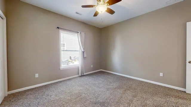 an empty room with windows and chandelier fan