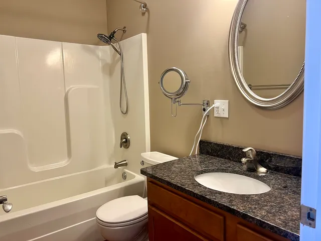 a bathroom with a granite countertop sink mirror toilet and bathtub