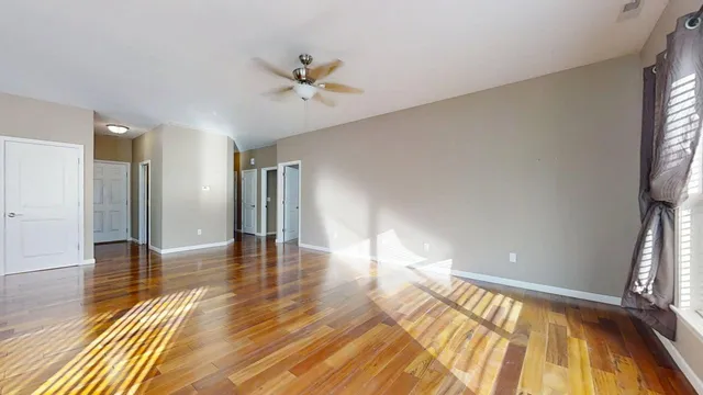 a view of empty room with wooden floor and fan