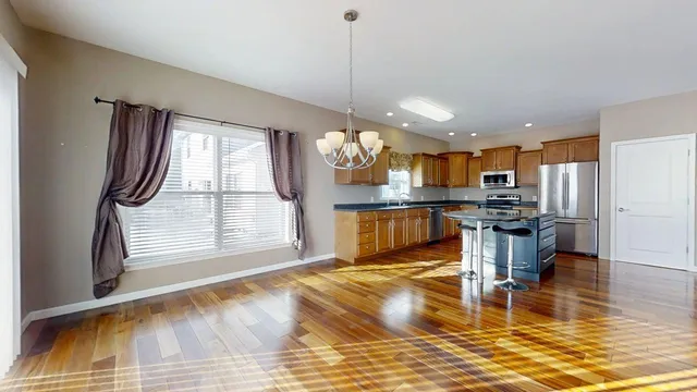 a kitchen with stainless steel appliances granite countertop a refrigerator a stove and a wooden floor