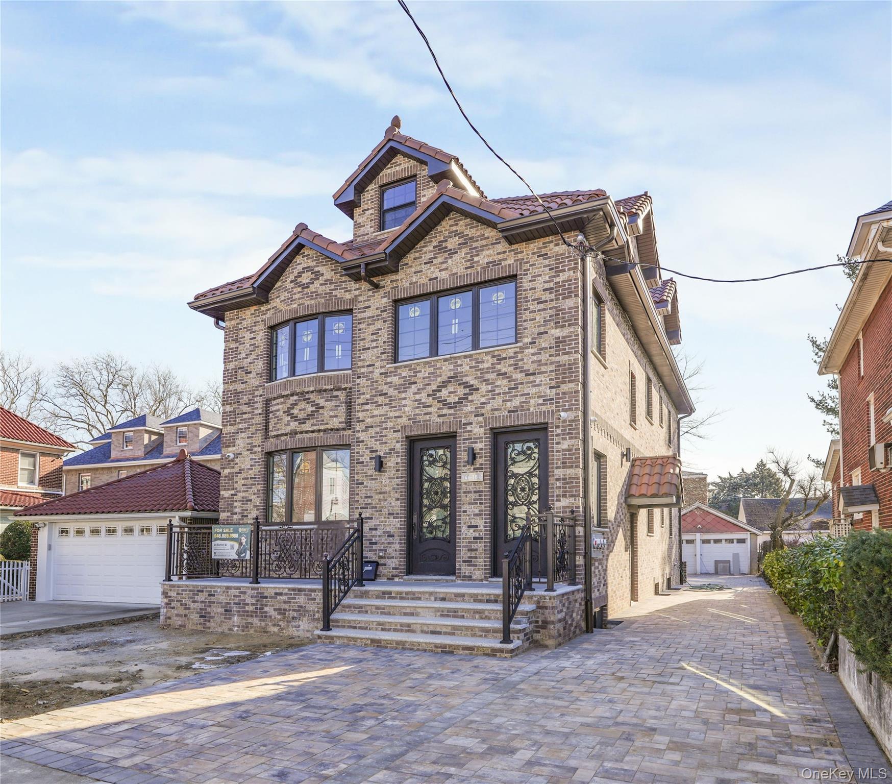 View of front of property with brick siding, an outbuilding, and a garage