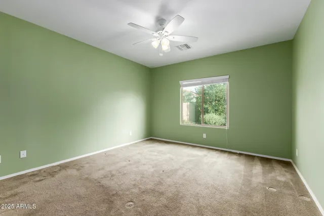 an empty room with windows and ceiling fan