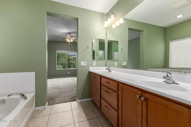 a spacious bathroom with a tub sink and mirror