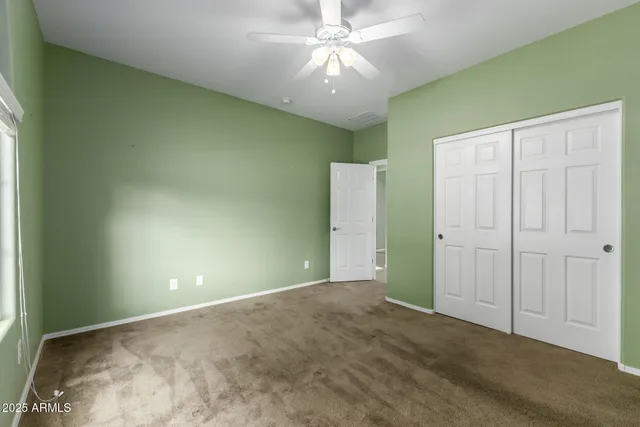 a view of an empty room and chandelier fan